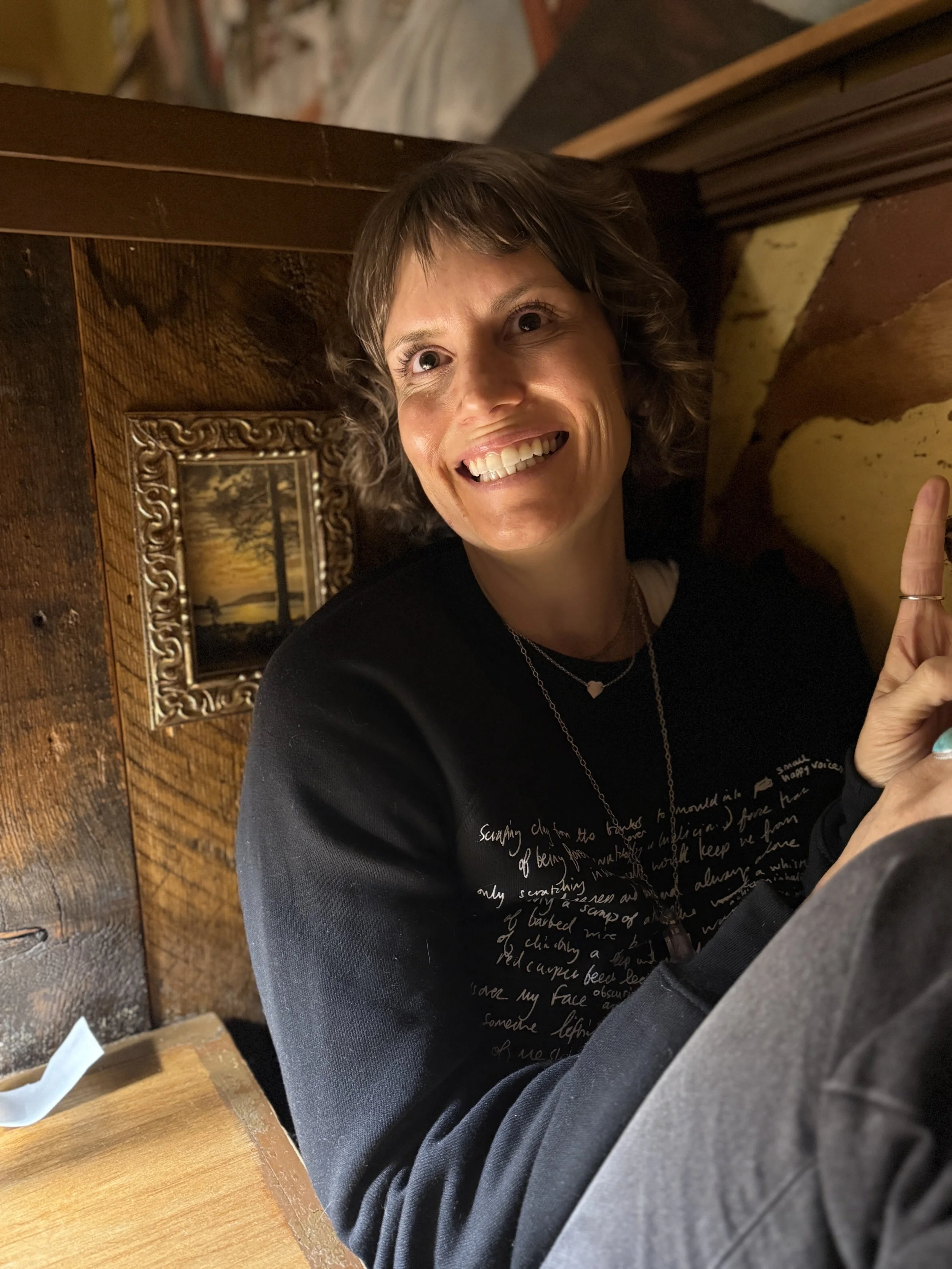 Jen Lescher smiling in a tight space near a picture frame. Jen offers OCD therapy in Boston, MA & online in San Diego, CA. Start working with a supportive therapist today.